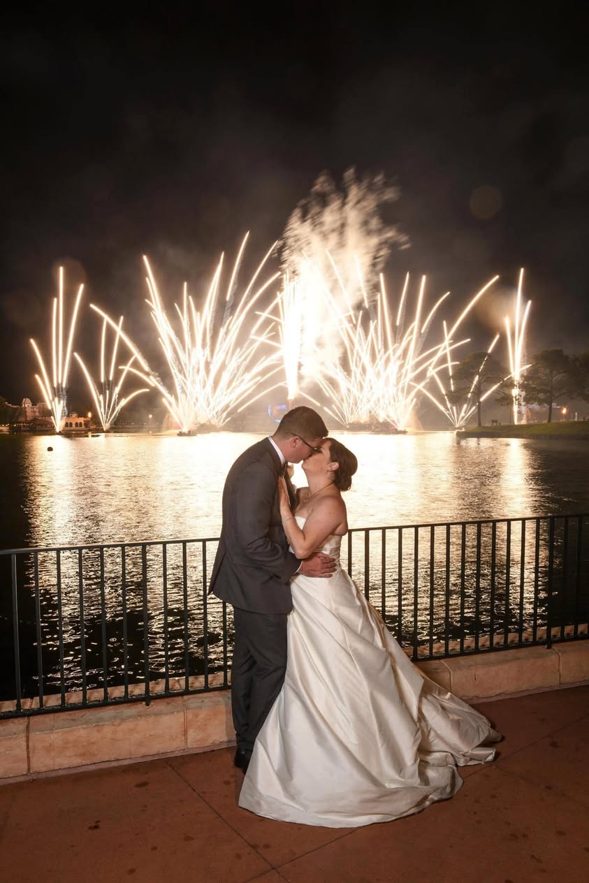 Laura and her husband kissing beside the lagoon during a Walt Disney World fireworks show