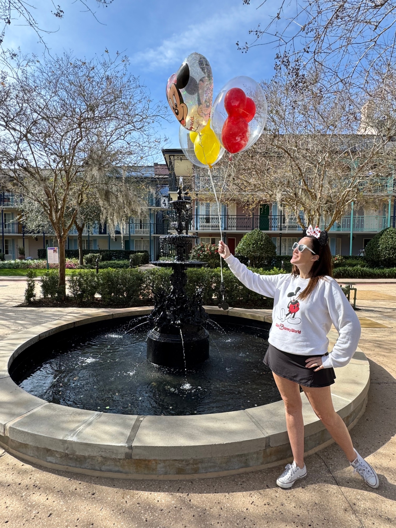 Alexis with Mickey balloons in front of a Disney fountain